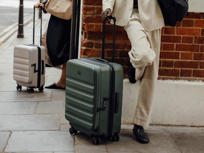 a man in a suit leaning against a wall with luggage