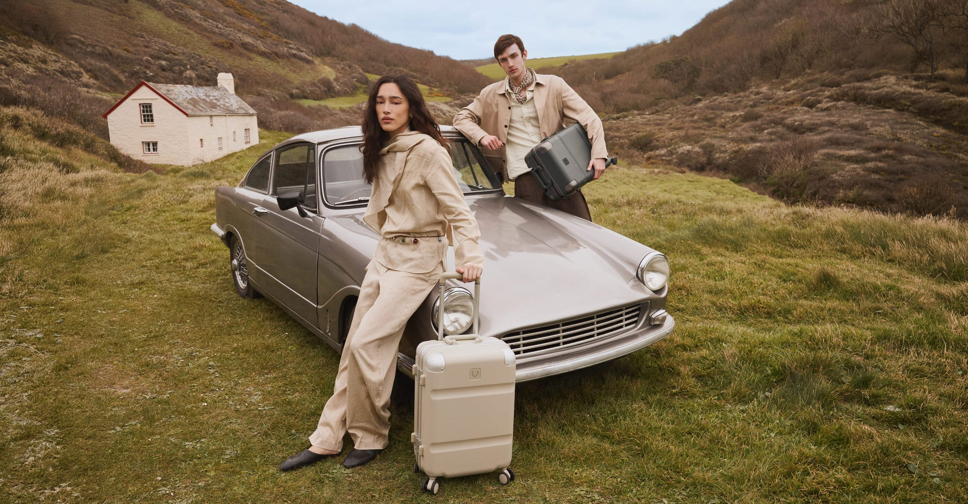a man and woman standing next to a car with luggage
