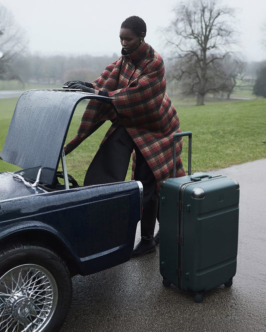 a person in a blanket standing next to a car with luggage