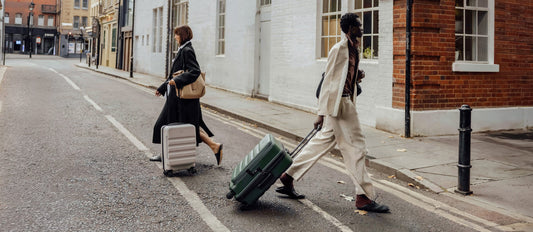 a man and woman walking with luggage on the street