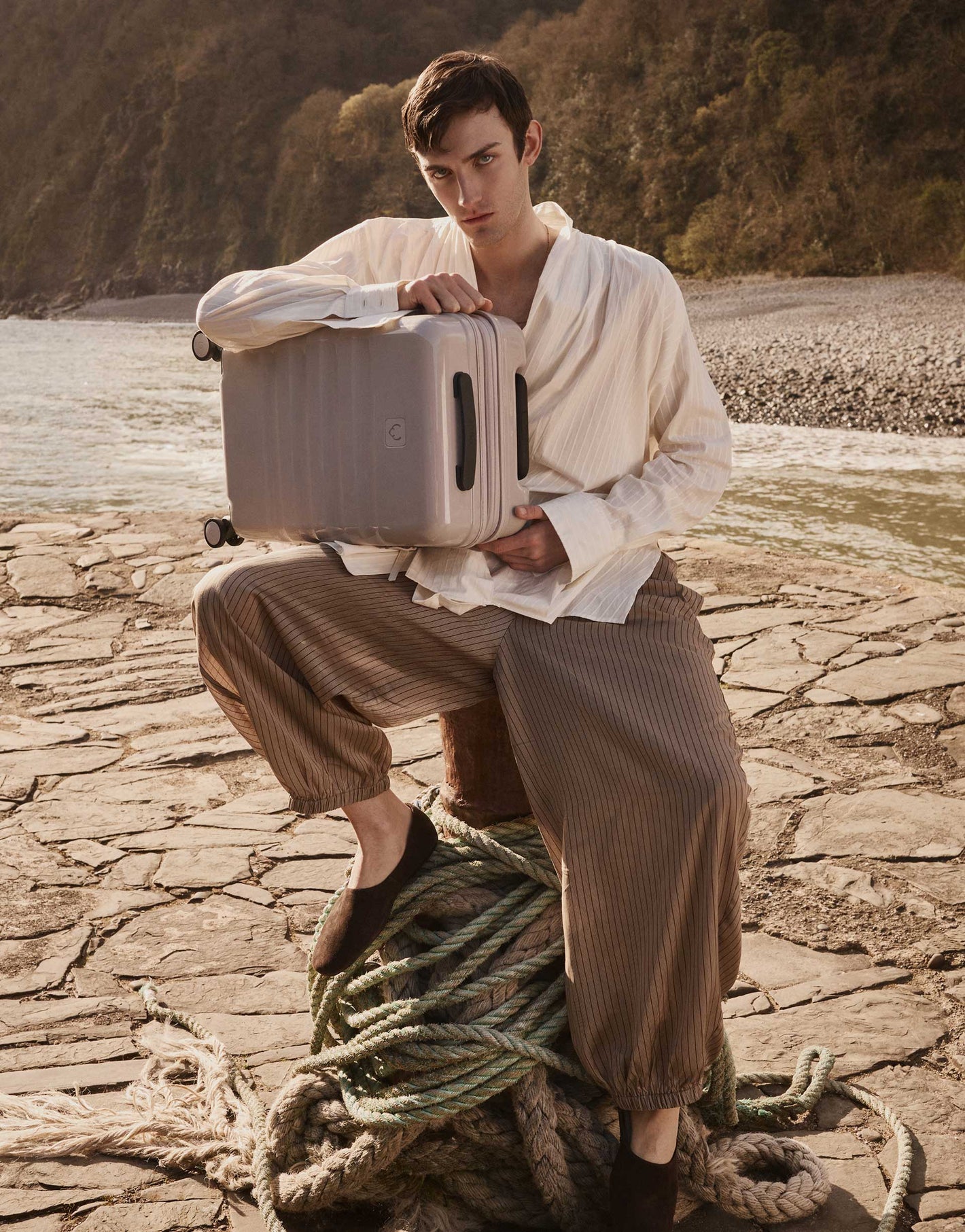 a man sitting on a rope holding a suitcase