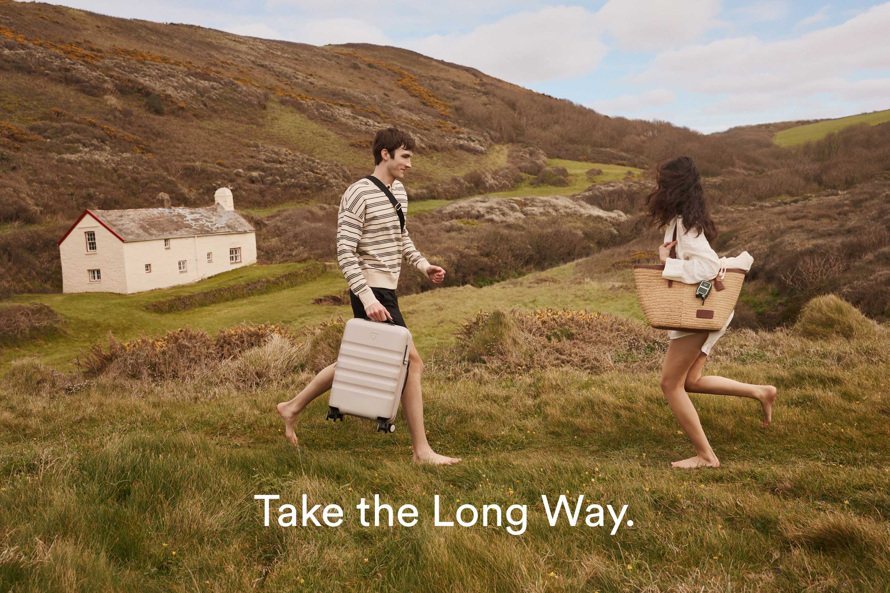 a man and woman running with luggage in a grassy field