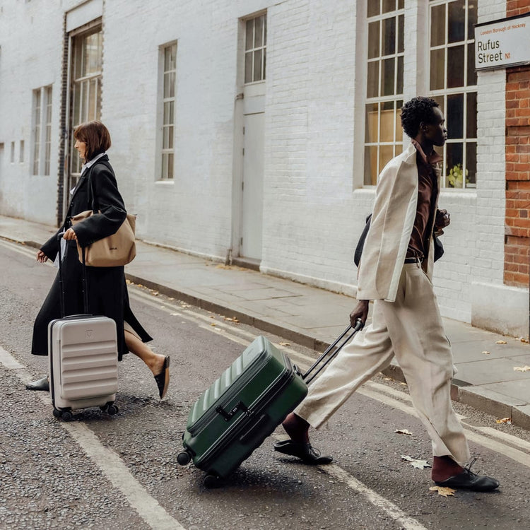 a man and woman walking with luggage on the street