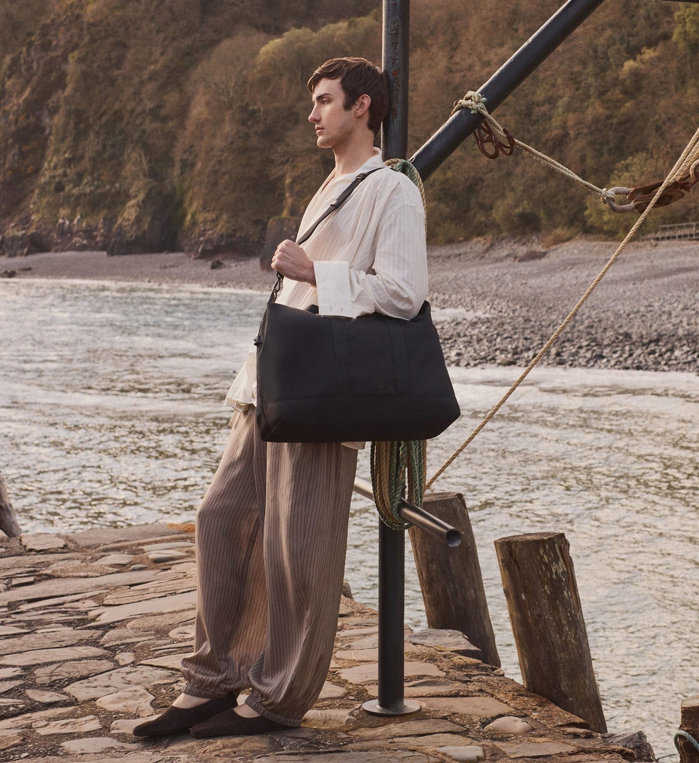 a man standing on a dock with a large black bag