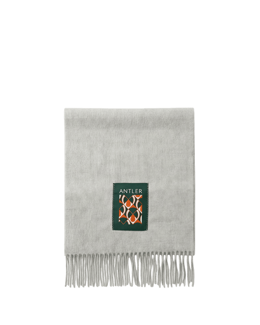 a grey scarf with a green square and white fringe