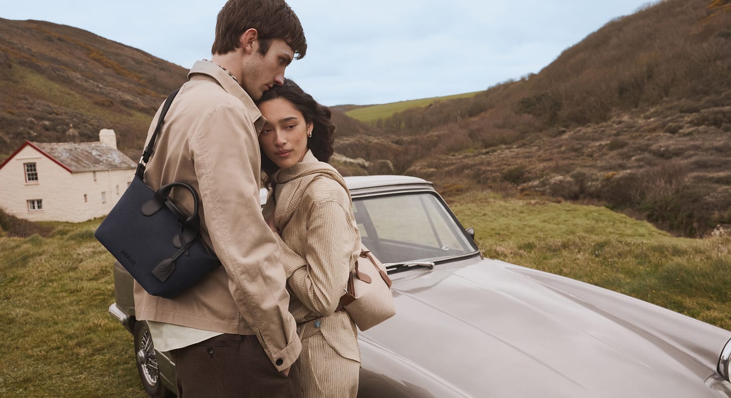 a man and woman hugging in front of a car