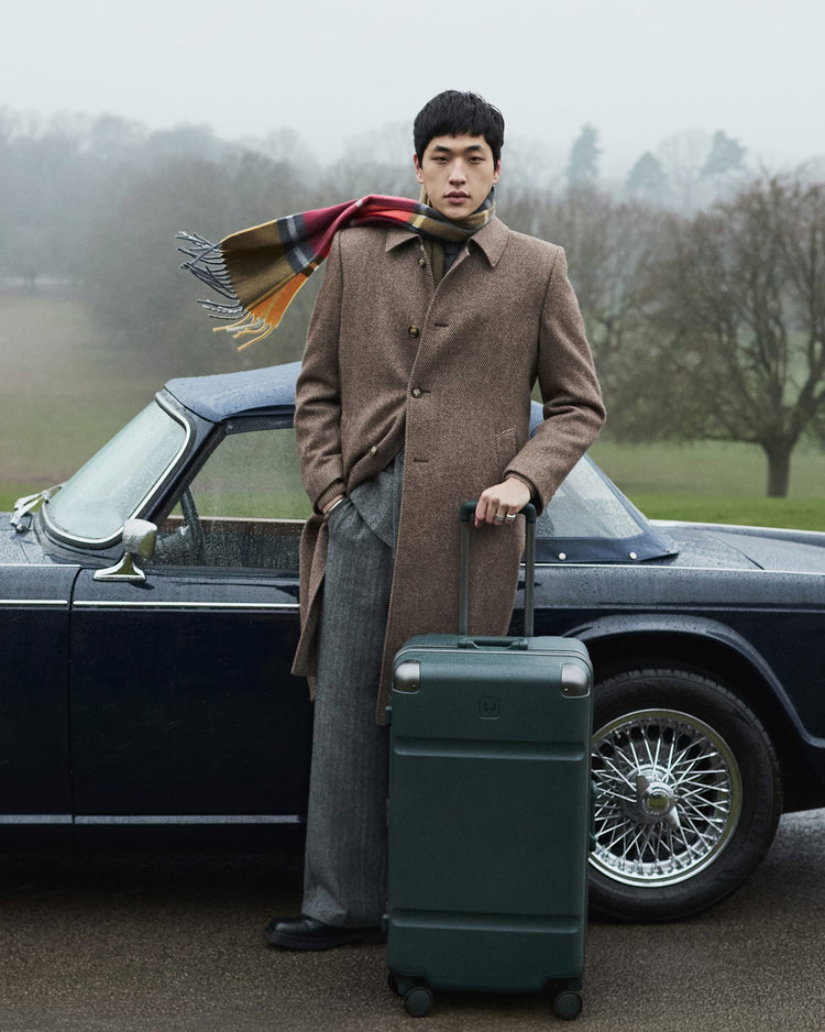 a man standing next to a car with a suitcase