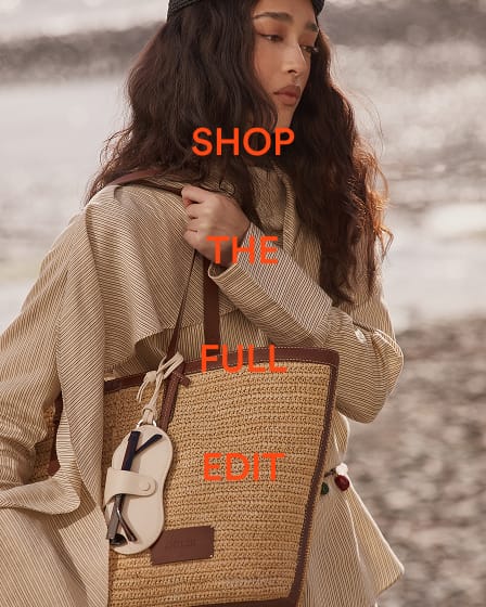 a woman with long brown hair and a straw bag