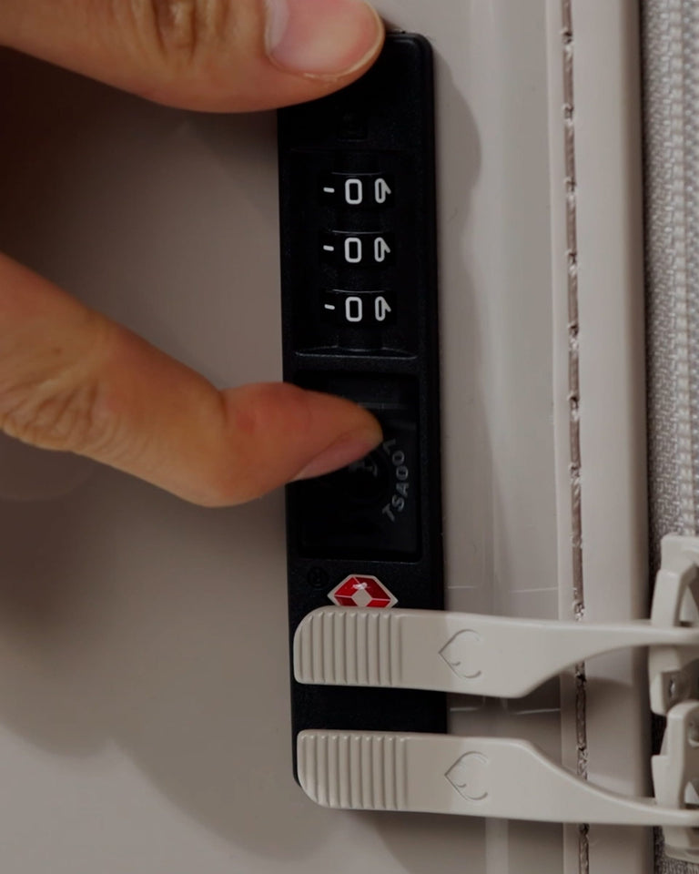 a finger pressing a keypad on a suitcase