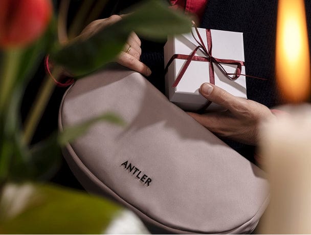 a person holding a small white box and a pink purse