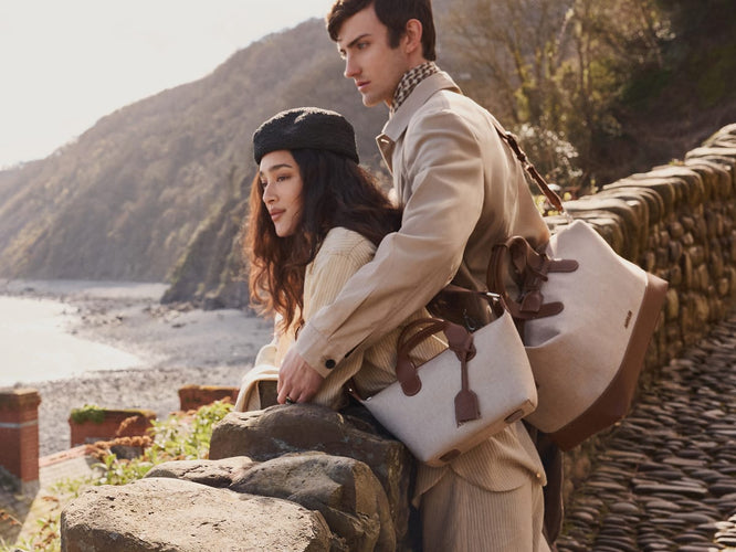 a man and woman leaning on a stone wall
