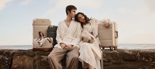 a man and woman sitting on a rock with luggage