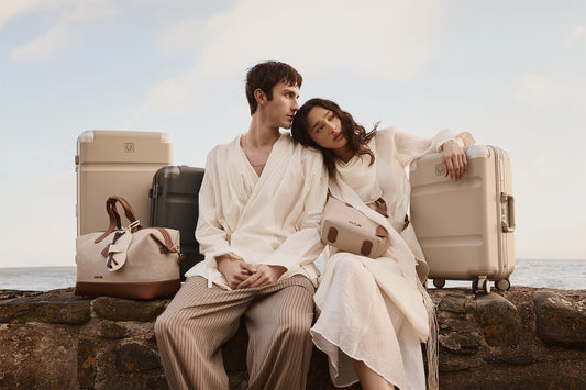 a man and woman sitting on a stone ledge with luggage
